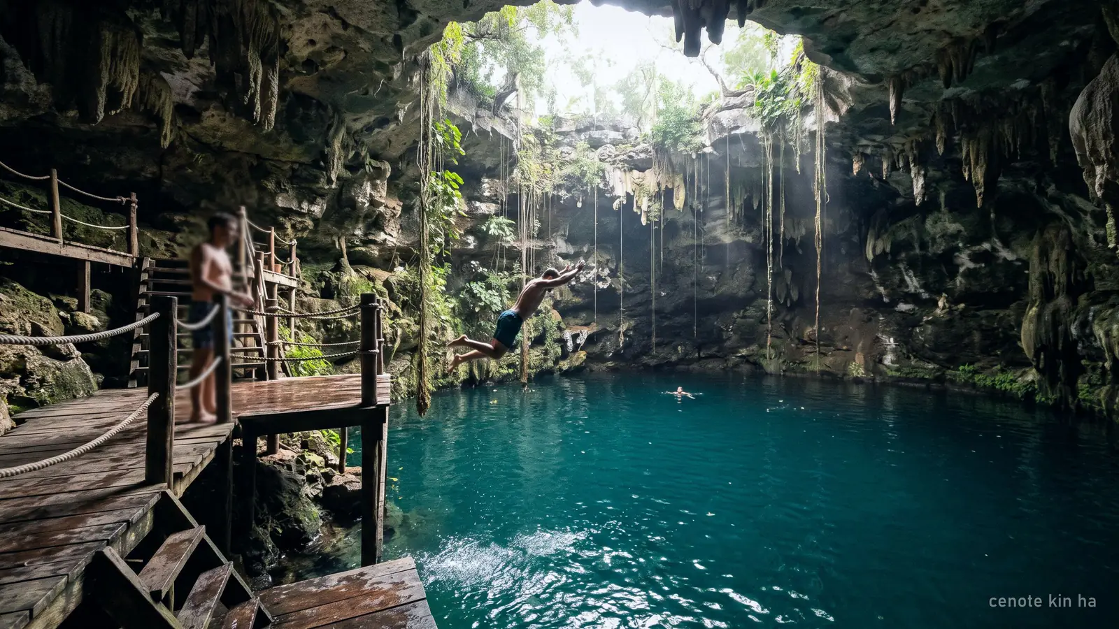 A cavern cenote with a wooden platform and a person jumping into the water